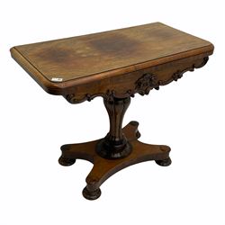 Victorian rosewood card table, swivelling rounded rectangular fold over top with moulded edge, the shaped apron with applied carved scroll and cartouche mounts, lobe carved pedestal support on shaped platform, turned and carved feet with recessed castors 