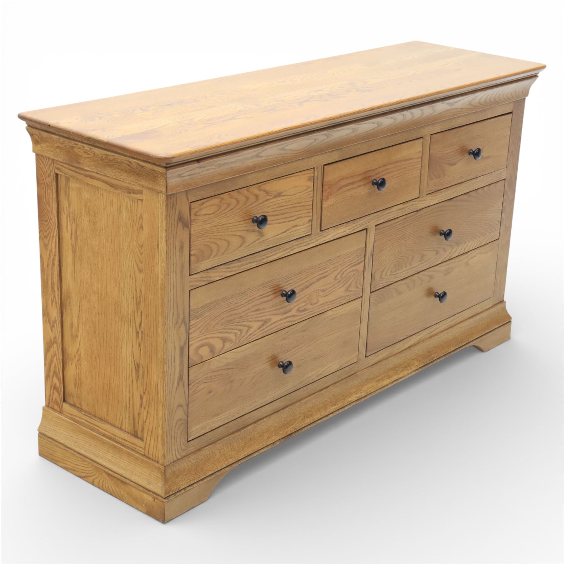 Contemporary oak veneered sideboard, moulded rectangular top above a six drawer arrangement, three over three, each drawer with turned ebonised style knob handle, panelled ends, raised on a shaped plinth base with bracket feet