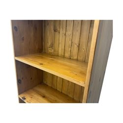 Early 20th century pine bookcase, projecting cornice over arched open shelving area with four fixed shelves, on shaped plinth base