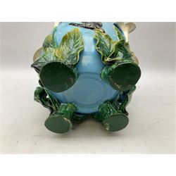 George Jones style majolica jardiniere of globular form, supported on four feet formed from modelled lily leaves growing up the side of the pot, with swallows flying amongst the white lily flowers, all set against a blue ground, with a pink interior, H27cm