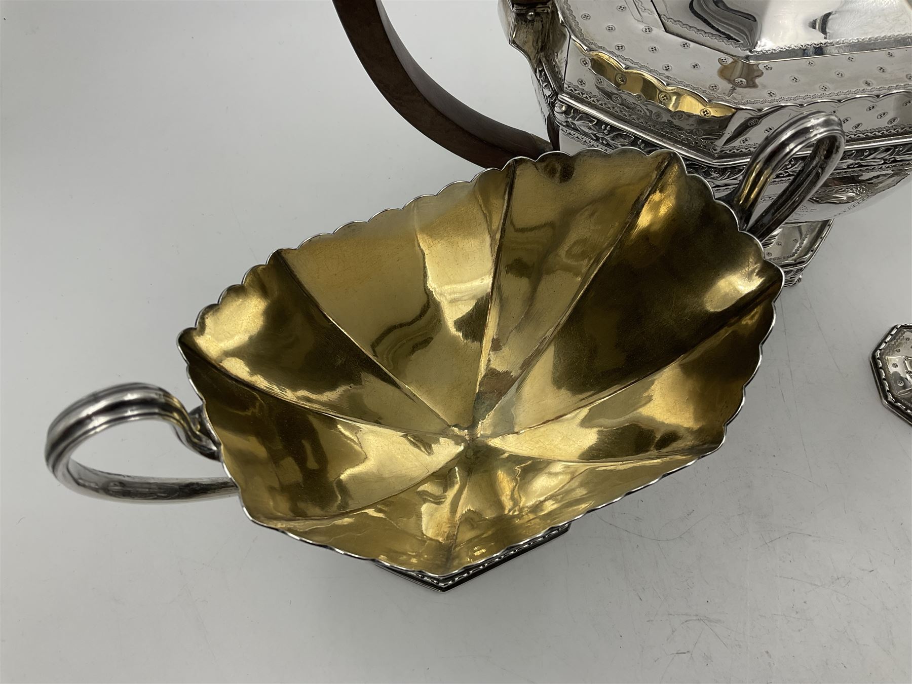 Victorian silver four piece tea service, comprising teapot, teapot stand, twin handled open sucrier and milk jug, each of octagonal form with foliate bud border and engraved decoration including crest to canted panels, and vacant panels, the teapot with ivory finial to the hinged cover and later wooden handle, hallmarked Edward Barnard & Sons Ltd, London1896, teapot including finial H15cm, milk jug including handle H16cm, teapot stand W11.5cm

This item has been registered for sale under Section 10 of the APHA Ivory Act