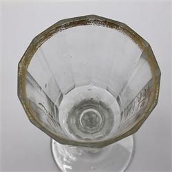 Three 18th century wine glasses comprising a plain stemmed glass with bell shaped bowl and conical folded foot H16cm, another plain stemmed glass with ogee bowl and folded foot and a Continental glass with gilt faceted bowl, decorated with male figure within a landscape, on a clear Silesian seven sided cut stem (3)