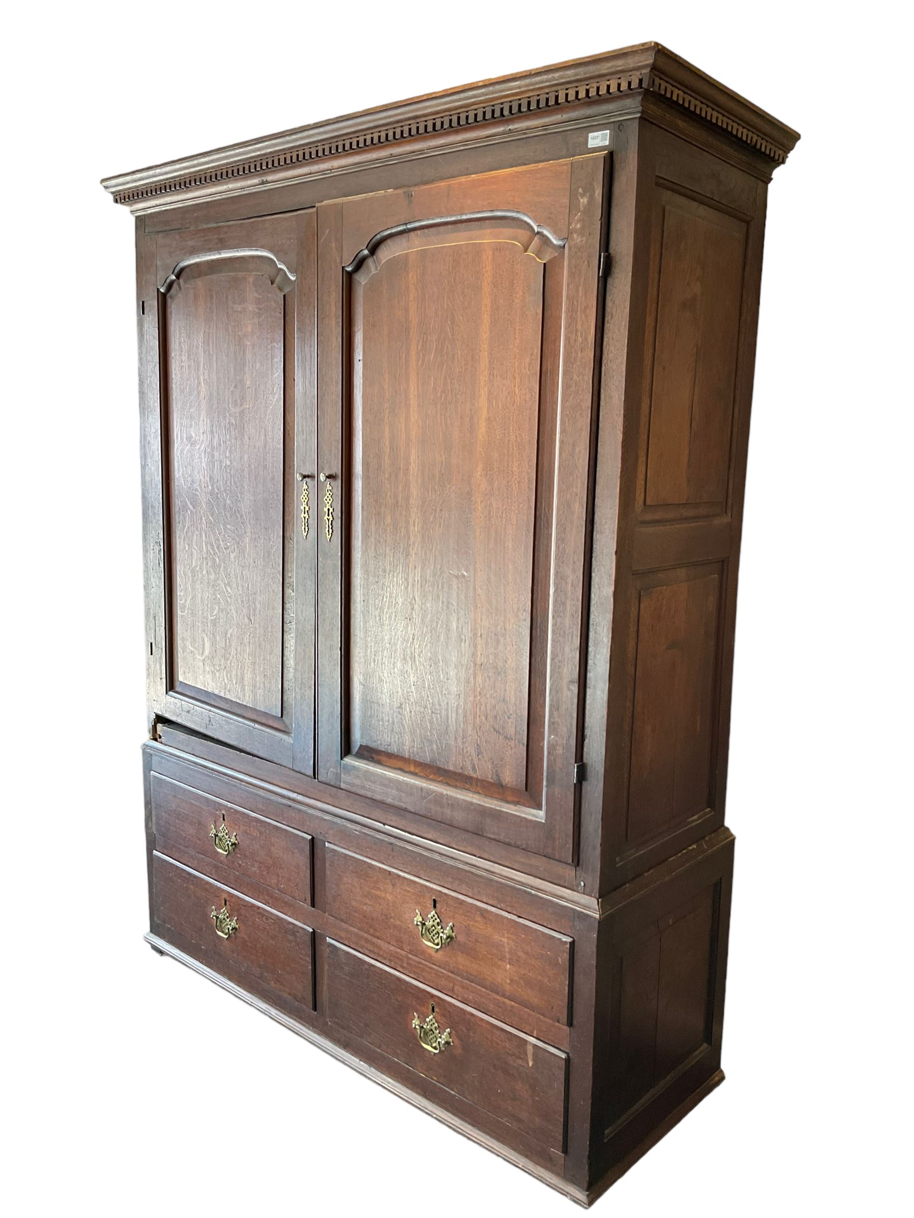 George III oak press cupboard, dentil cornice over two arch fielded panel doors, the base fitted with four drawers with pressed brass handle plates