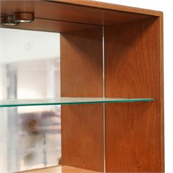 G-Plan - ‘Fresco’ teak bookcase cabinet, rectangular open bookcase with mirrored back panel to the upper section, fitted with a single glass display shelf and two wooden shelves below, the base enclosed by a pair of cupboard doors with shaped teak handles, on a plinth base