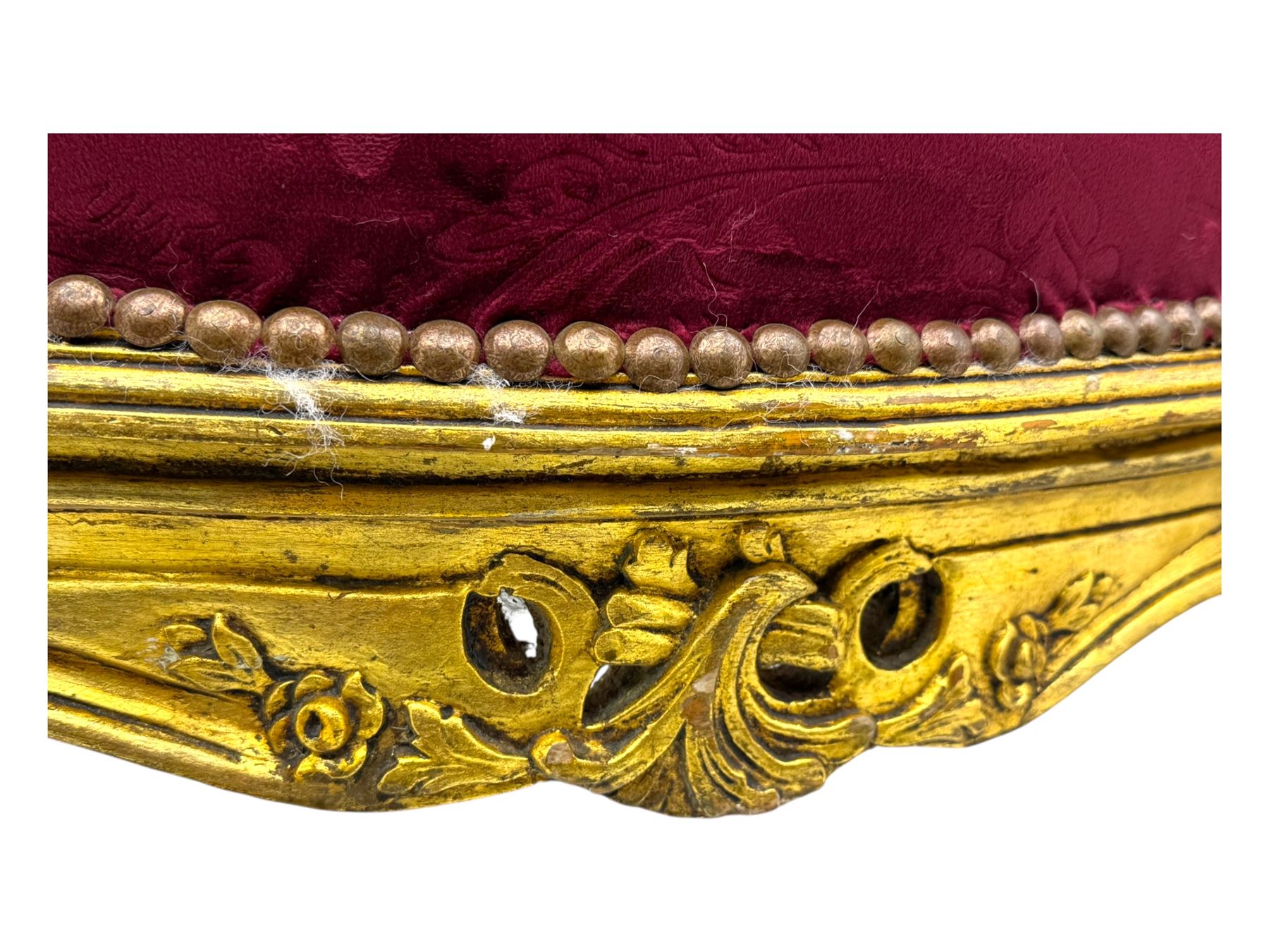 Pair of Louis XV-design giltwood stools, each upholstered in red damask fabric with slight variations in patterns, the carved frames adorned with scrolling foliage and shell motifs, raised on cabriole supports