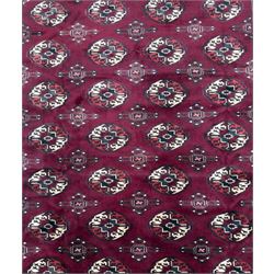 Northeastern Persian Yamut  hand-knotted carpet, the rich burgundy field with repeating rows of stepped gul motifs in cream and black, enclosed by multiple linear and geometric borders with hooked motifs and diamond medallions