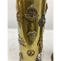 WW1 German brass shell case inscribed PATRONENFABRIK KARLSRUHE 1917 decorated with a large Chinese style dragon H50cm; and another brass 105mm shell case dated 1968 applied with twenty-eight Staybrite and other cap badges including Rhodesia, Royal Marines, Canadian Light Infantry, 17th lancers, RAOC, REME, Military Police etc H37cm (2)