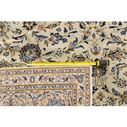 Central Persian Kashan hand-knotted rug, ivory field intricately decorated with an all-over design of scrolling vines, palmettes, and stylized lotus motifs in shades of soft blue, pale gold, and indigo within floral borders