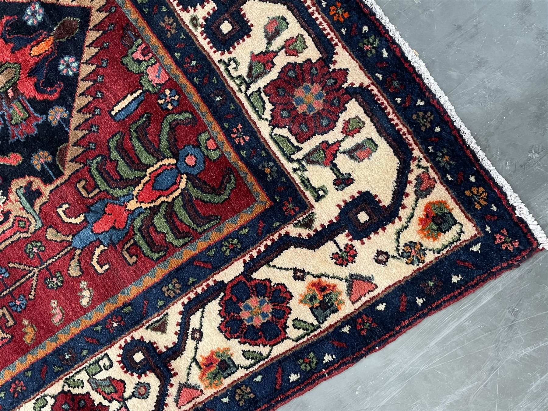 Persian Hamadan rug, the red ground field decorated with two floral medallions and stylised flower heads, repeating guarded border