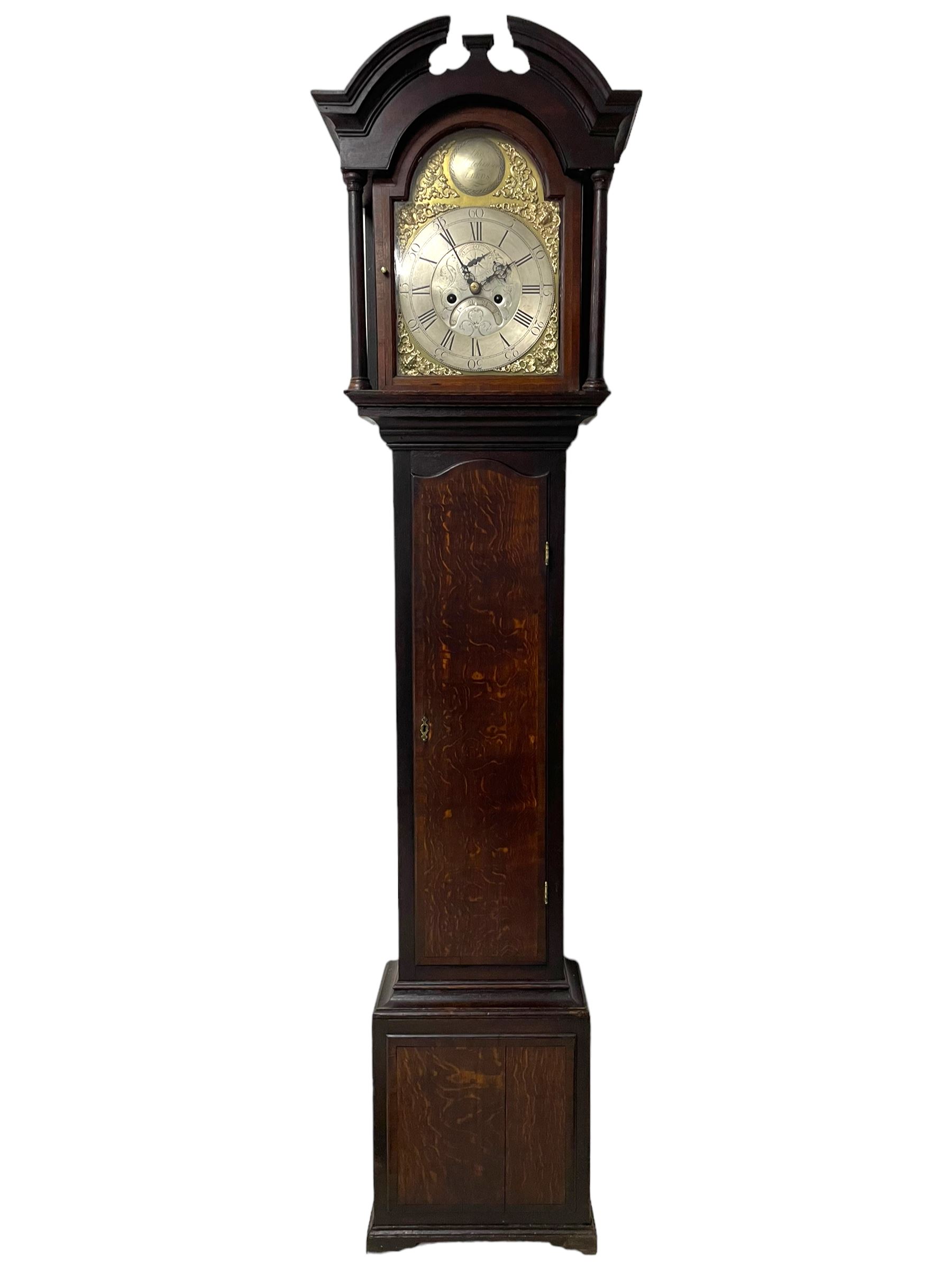 Thomas Hutchinson of Leeds - 18th century 8-day oak longcase clock with as broken arched  pediment and moulded cornice, with a conforming hood door flanked by plain turned pilasters with gesso capitals,  long trunk door with a wavy top on a square plinth with a raised panel, brass dial with cast spandrels,  engraved silvered dial centre and chapter ring with Roman numerals, five minute Arabic's and minute track, with pierced steel hands, seconds pointer,  arched calendar aperture and silvered boss engraved with the makers name to the break arch, dial pinned to a rack striking two train movement with a recoil anchor escapement. With weights and pendulum. Thomas Hutchinson is recorded as working in Leeds from 1760-90.