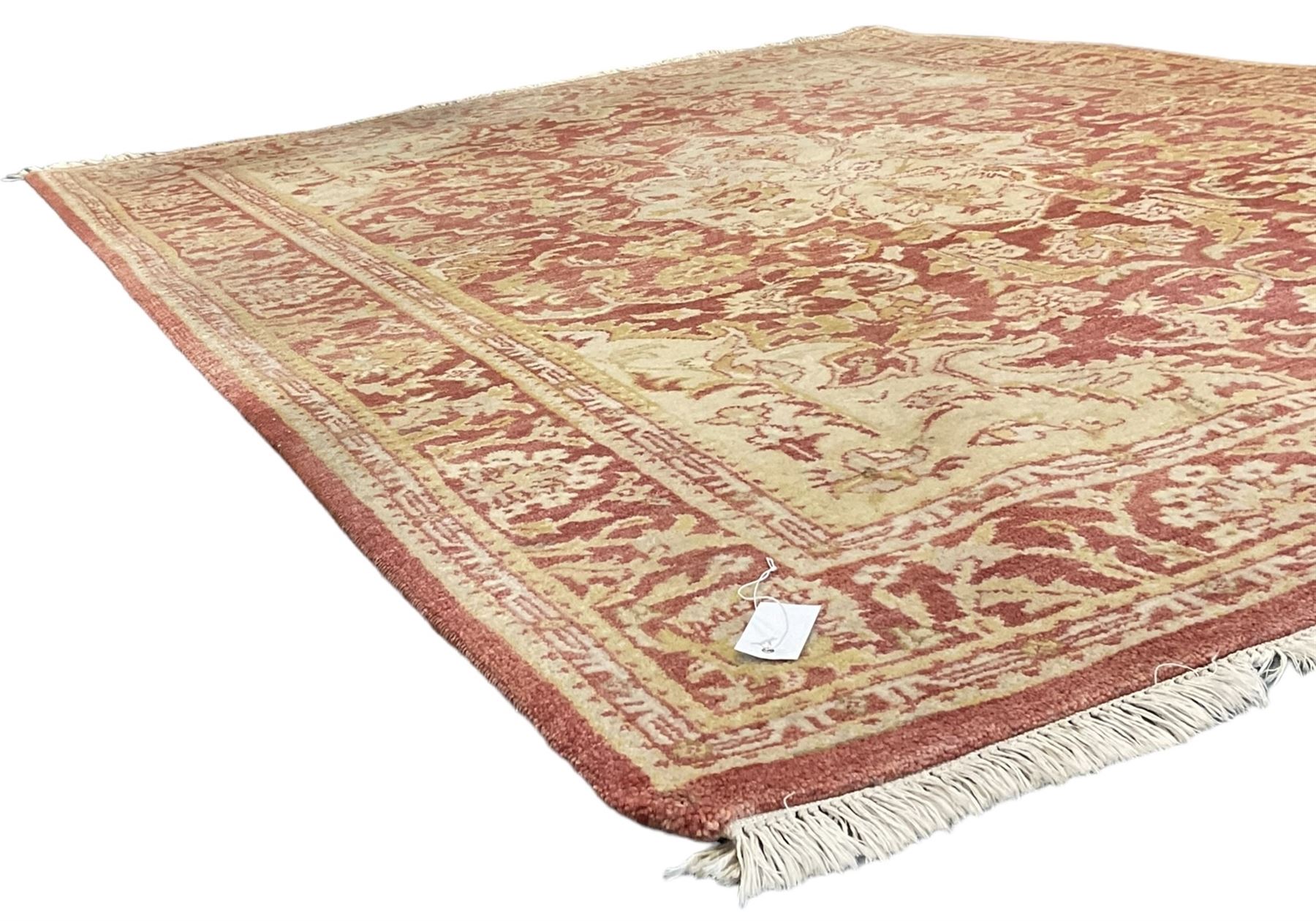 Persian design beige and crimson ground rug, the field decorated with interlacing scrolled foliage, repeating border within guard stripes 
