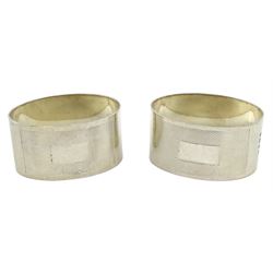 Pair of mid 20th century silver napkin rings, both of oval form, with engine turned decoration and vacant rectangular panel to front centre, hallmarked Birmingham 1944, maker's mark indistinct, approximate total weight 2.97 ozt (92.4 grams)