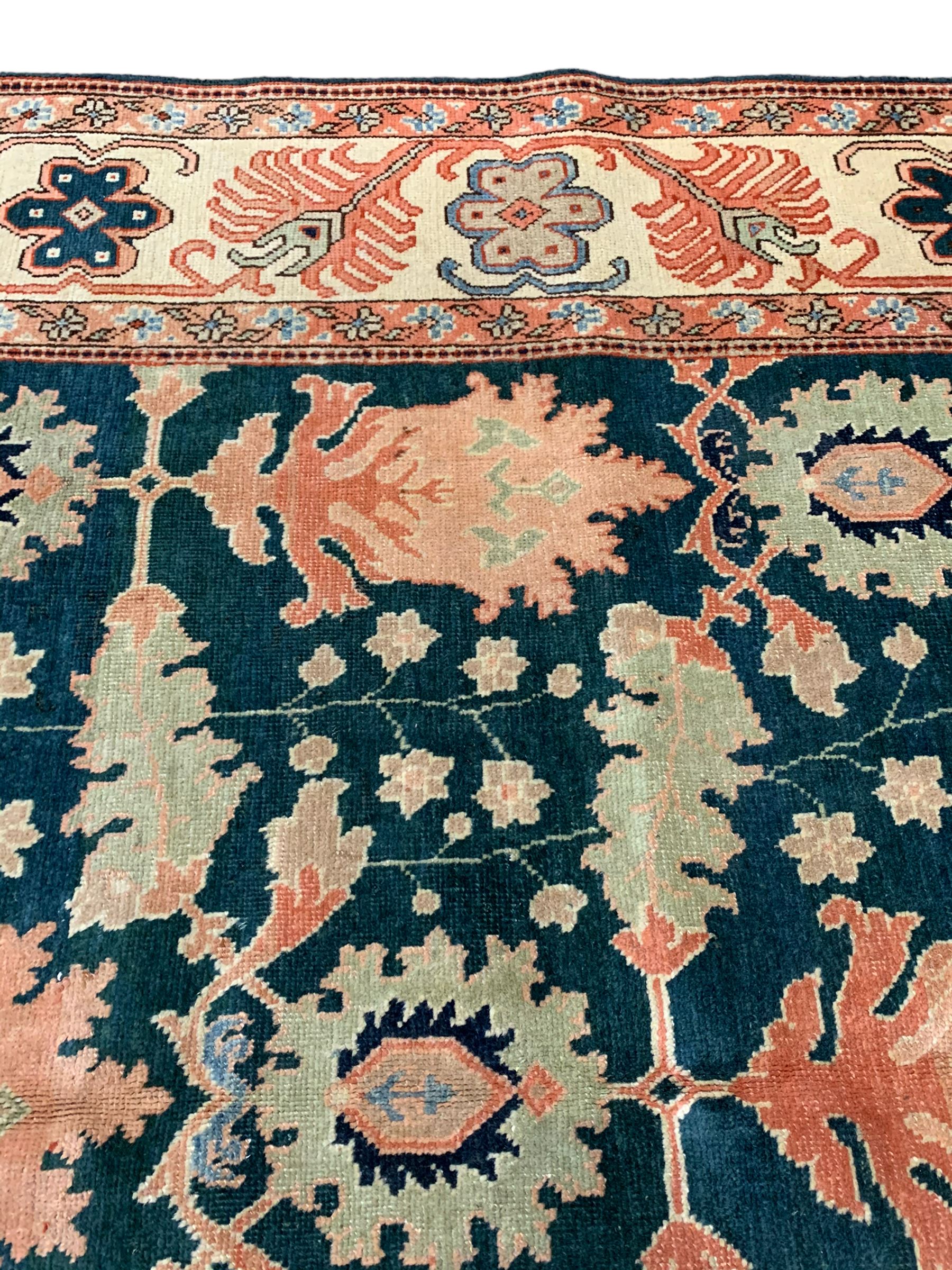 Persian emerald green ground rug, the field decorated with large stylised plant motifs, ivory ground border with repeating leaf motifs, the guards decorated with trailing branch and flowerhead motifs