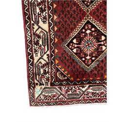 Persian Baluch red ground runner, seven lozenge medallions each decorated with stylised floral motifs, ivory border decorated with trailing pattern and Boteh motifs, within geometric guard stripes 