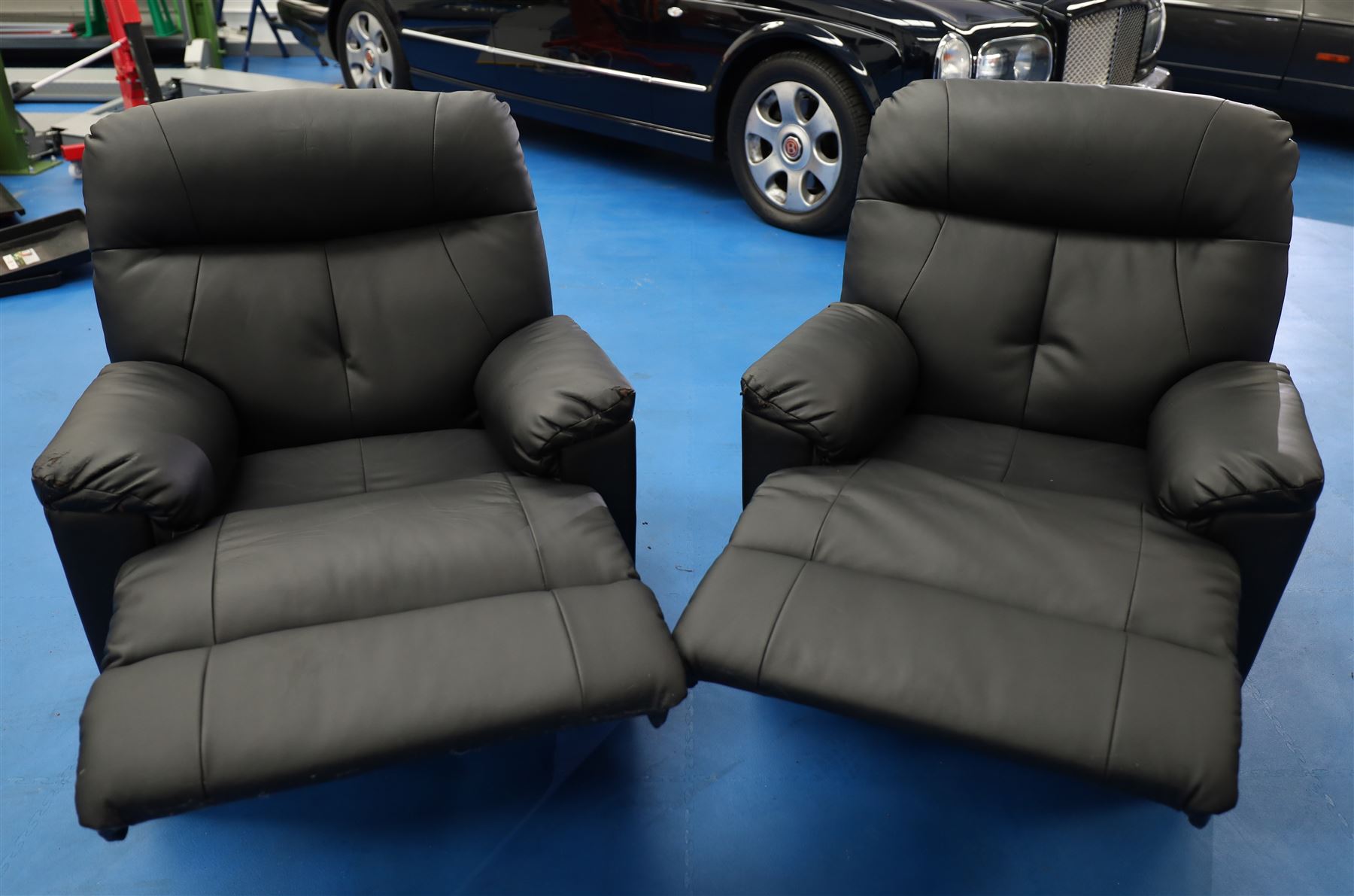Two reclining armchairs upholstered in black faux leather