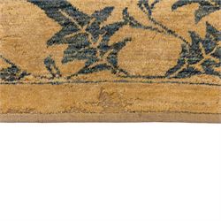 Late 20th century Turkish hand-woven carpet, golden beige field decorated with a repeating lattice of stylized medallions enclosing boteh and angular foliate motifs linked by issuing scrolling vinery within a border of complementary stylized leaf scrolls