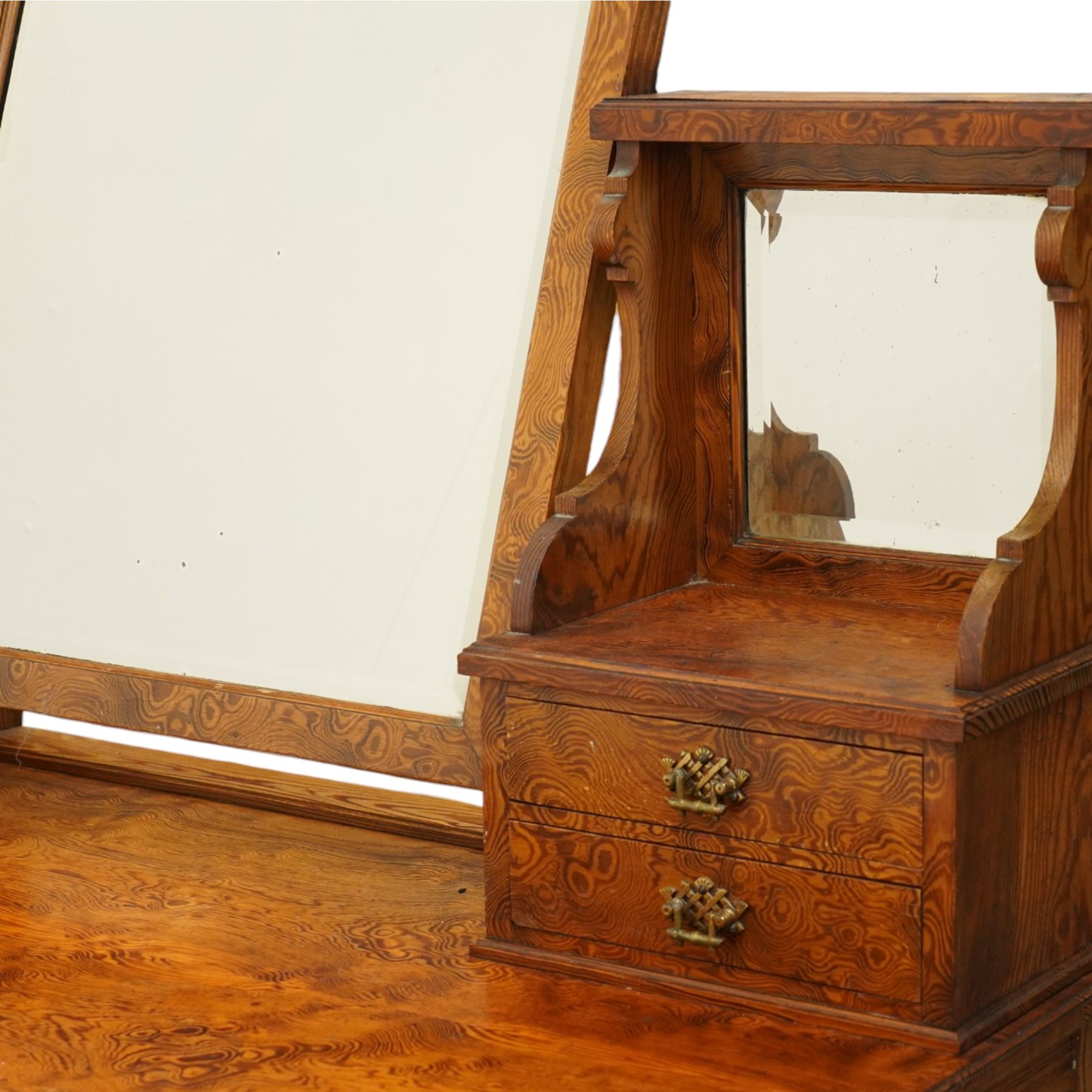 Late Victorian figured pitch pine dressing table, the rectangular swing mirror with shaped cresting flanked by mirrored superstructures, one with a three-quarter galleried shelf, fitted with two drawers, rectangular over two frieze drawers fitted with pierced brass lattice handle plates, raised on ring-turned tapering legs with brass castors