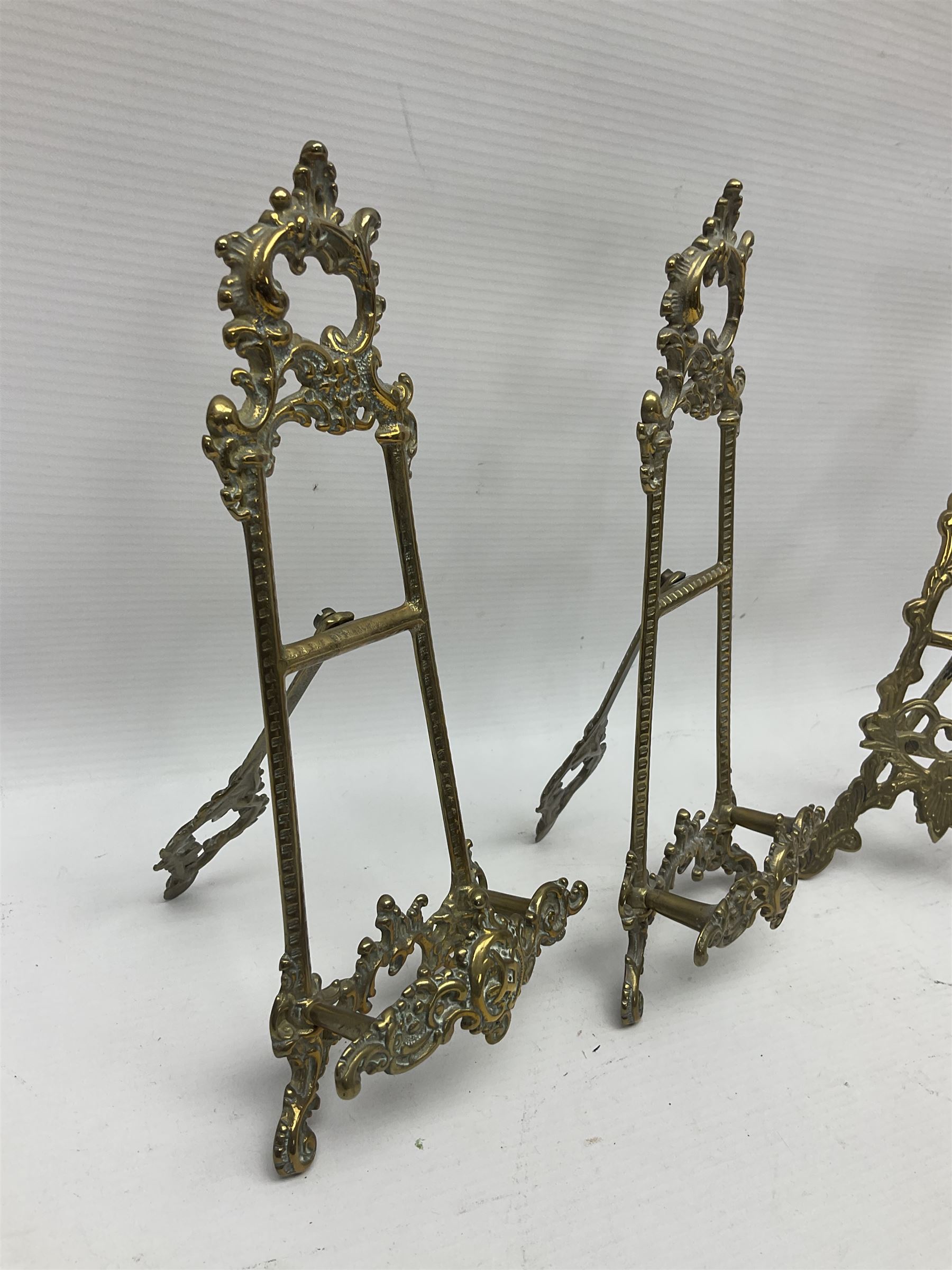 Nine ornate cast brass easel stands of various sizes, H24cm