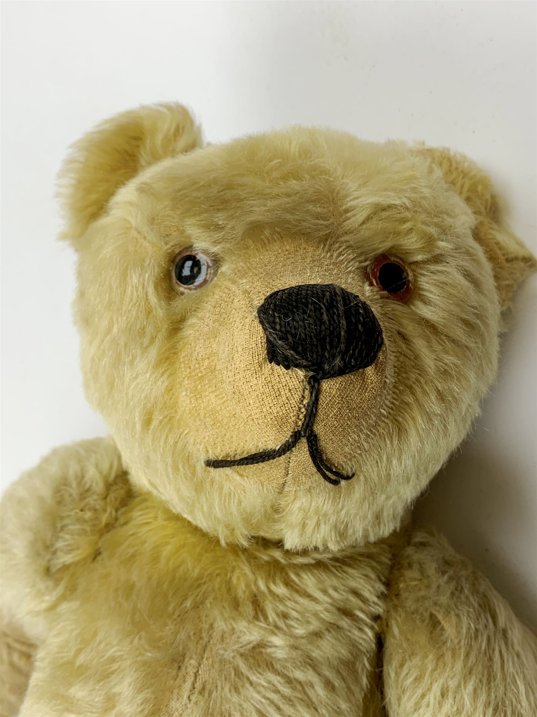 Chad Valley large teddy bear c1930s with wood wool filled blond mohair body, jointed swivel head with glass eyes, shaved muzzle with vertically stitched nose and mouth and jointed limbs H21