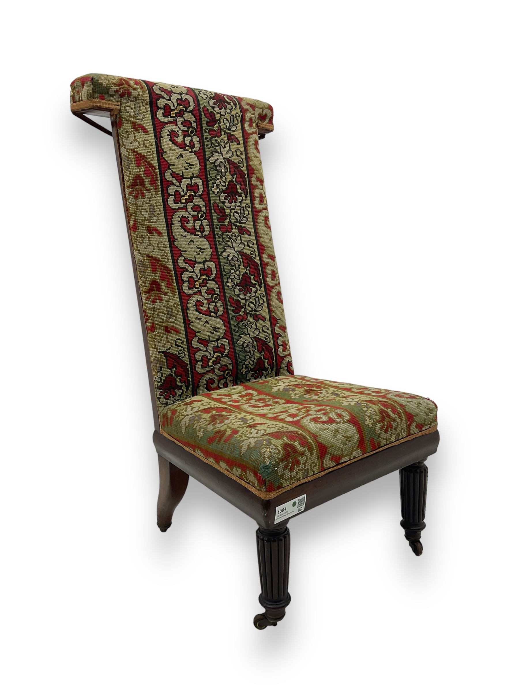 19th century mahogany framed prie-dieu chair, upholstered in red and green patterned fabric, high back with rolled top, standing on turned front supports with castors