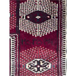 Northeastern Persian Yamut  hand-knotted carpet, the rich burgundy field with repeating rows of stepped gul motifs in cream and black, enclosed by multiple linear and geometric borders with hooked motifs and diamond medallions
