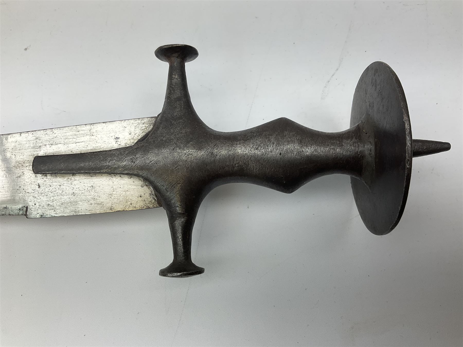 19th Century Indian Tulwar sword with 77cm single edged, slightly curved fullered blade;  steel crossguard, langets, grip and spiked disc pommel with stiff leaf decoration L90cm overall
