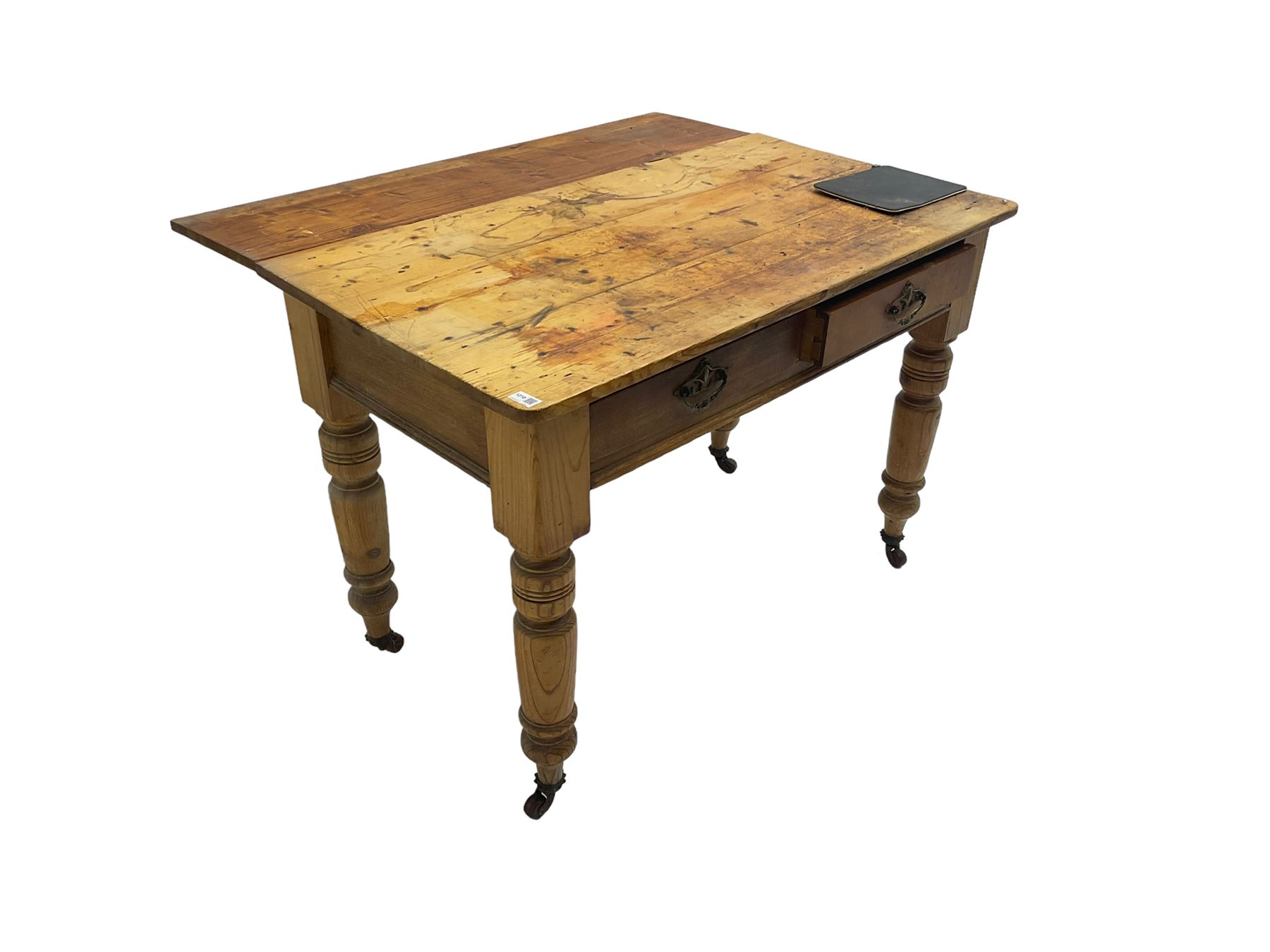 Traditional rustic pine dining table, rectangular top fitted with two drawers, raised on turned tapering supports on ceramic castors