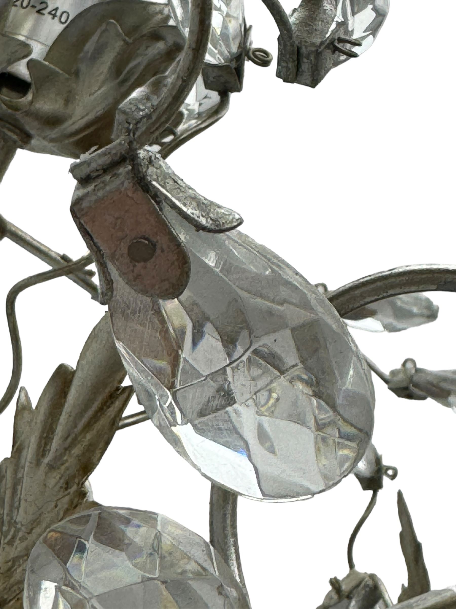 India Jane - silver finish metal chandelier, modelled with scrolling vines and leaves, embellished with faceted glass drops, fitted with six candle sconces, and wired for electricity