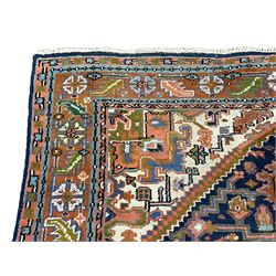 Persian Heriz indigo and rust ground rug, central geometric star medallion decorated with stylised foliate motifs, the border decorated with stylised flower heads