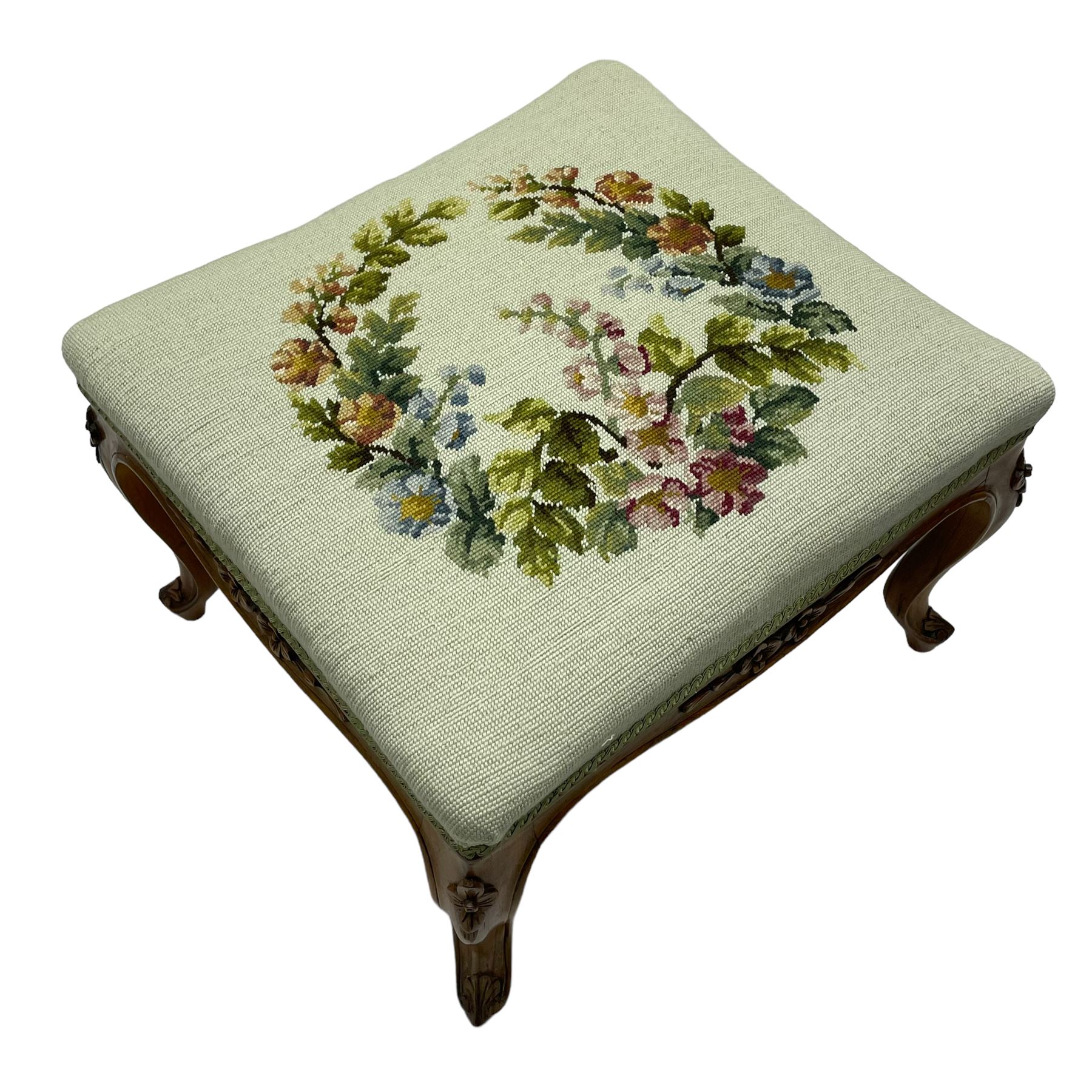 19th century French walnut dressing stool, rectangular seat upholstered in a floral needlework tapestry top, shaped apron with applied carved flower heads, on cabriole supports with acanthus carved feet