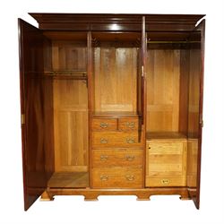 Edwardian mahogany triple combination wardrobe, the moulded cornice above a central panel door inlaid with foliate detail, flanked by full length mirrored doors, the interior fitted with hanging compartments and a central bank of two short and three long drawers, raised on a shaped bracket feet