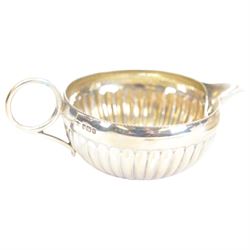 Edwardian silver shell butter dish, upon three bun feet, together with a matching shell spoon engraved with initial, both hallmarked Josiah Williams & Co, London 1906 and 1914, together with an Edwardian milk jug, open sucrier and sugar tongs, the jug and bowl of circular part fluted form with bead rim, hallmarked Mappin & Webb Ltd, Sheffield 1902, both sets contained within fitted tooled leather boxes with silk and velvet lined interiors