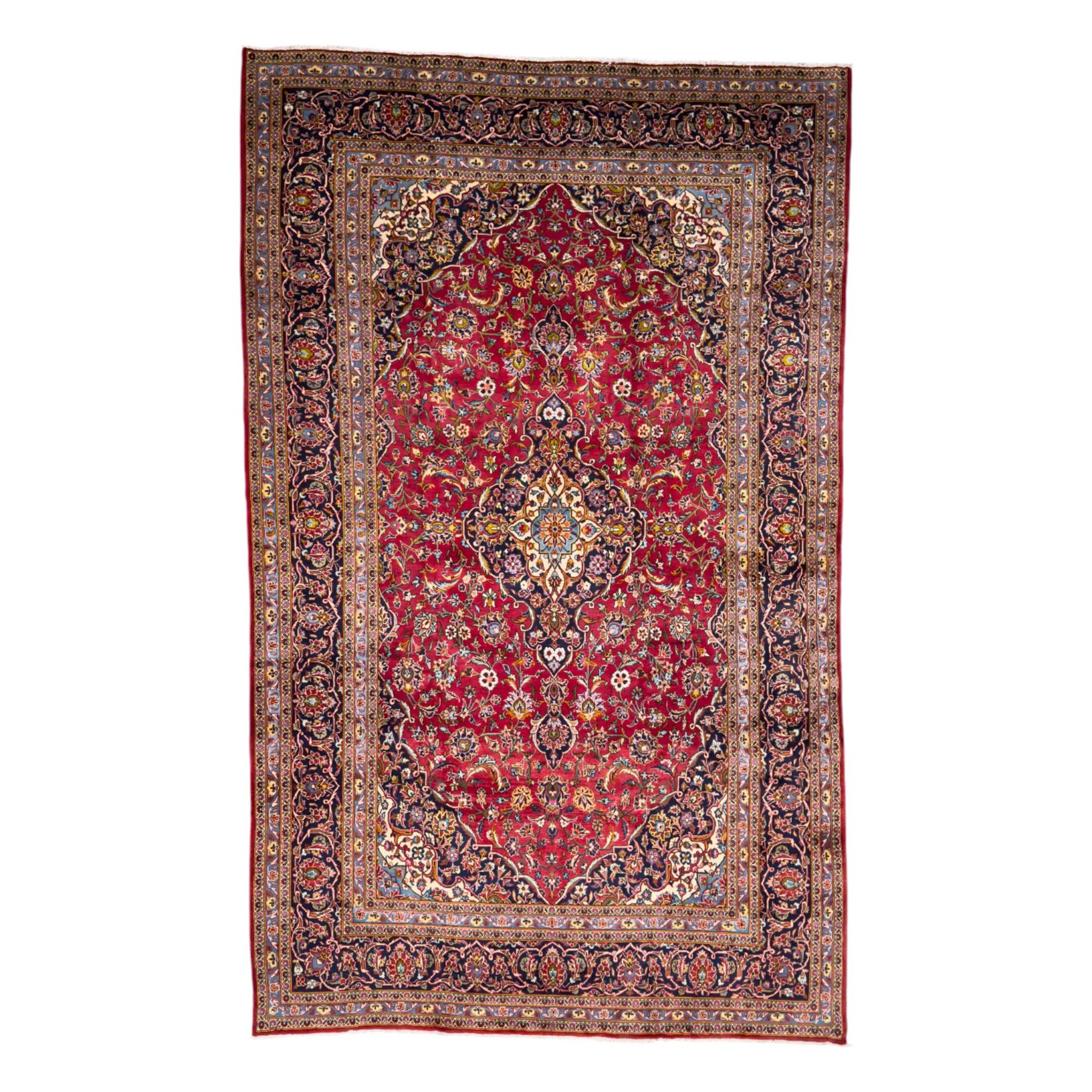 Central Persian Kashan hand-knotted carpet, the madder red field with central lobed medallion in indigo and ivory, enclosing scrolling arabesques and flowerheads, framed by palmette spandrels and an indigo border of rosettes and lotus forms between multiple floral guard stripes, from the region of Kashan