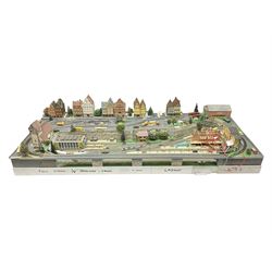 Table top 'N' gauge continental scenic layout as a split level town with various loops of track, station with numerous platforms, engine shed, assorted buildings, roads with motor vehicles and figures, tunnels, trees, river with bridge, tram depot etc 122 x 52cm