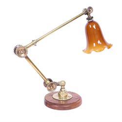 John Dugdill, early 20th century brass angle poise desk lamp, circa 1930's, with daisyhead joints and amber coloured lampshade, upon a circular wooden base 