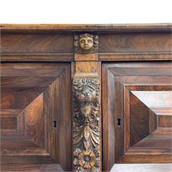 Late 17th century Flemish/Dutch rosewood and oak ‘Zeeuwse Kast’ or cupboard, projecting cornice carved with three putti masks, the uprights carved with lion masks over ribbons, flower heads and foliage, enclosed by four geometric panelled doors, lower central upright carved with flower head over foliate ribbon with bird among foliage, the escutcheon hidden by swivel berry carved cover, interior fitted with shelves, two drawers and shallow hinged cupboard, on two large turned and ebonised feet, circa 1680