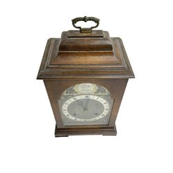 Imperial - English 1950s walnut and mahogany 8-day veneered mantle clock in an18th century-style case, with an inverted bell top and handle, break arch brass dial with a matted centre, silvered chapter ring with roman numerals and trefoil steel hands, cast spandrels and silvered Tempus Fugit boss to the arch, with a rack striking movement striking the hours and half hours on a gong. With pendulum and key.