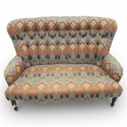 Late 20th century Liberty upholstered two seater sofa, the shaped back and arms with deep buttoned upholstery, covered in Art Nouveau fabric with stylised floral and foliate motifs, loose scatter cushions en suite, raised upon turned tapering front supports and swept rear legs