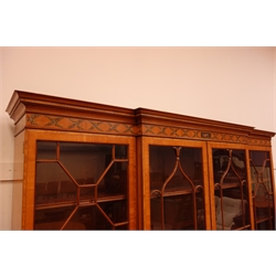  Sheraton Revival satinwood breakfront bookcase, frieze painted with scrolling leafage above four astragal doors with adjustable shelves, the base with four doors painted with floral sprays in oval panels, on a plinth base, W234cm, H235cm, D52cm  