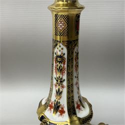 Pair of modern Royal Crown Derby Old Imari 1128 pattern candlesticks, each with shaped drip tray affixed to squat socket, upon spreading stem and canted square base with gilt dolphin edges, with printed marks beneath including Roman numeral year cypher for 2003, H26.5cm, with original boxes