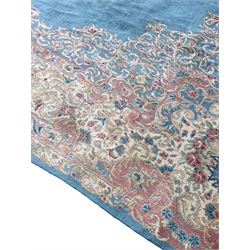 Large Persian design carpet, plain light blue field with floral design central medallion, scrolling foliate spandrels and borders decorated with flower heads