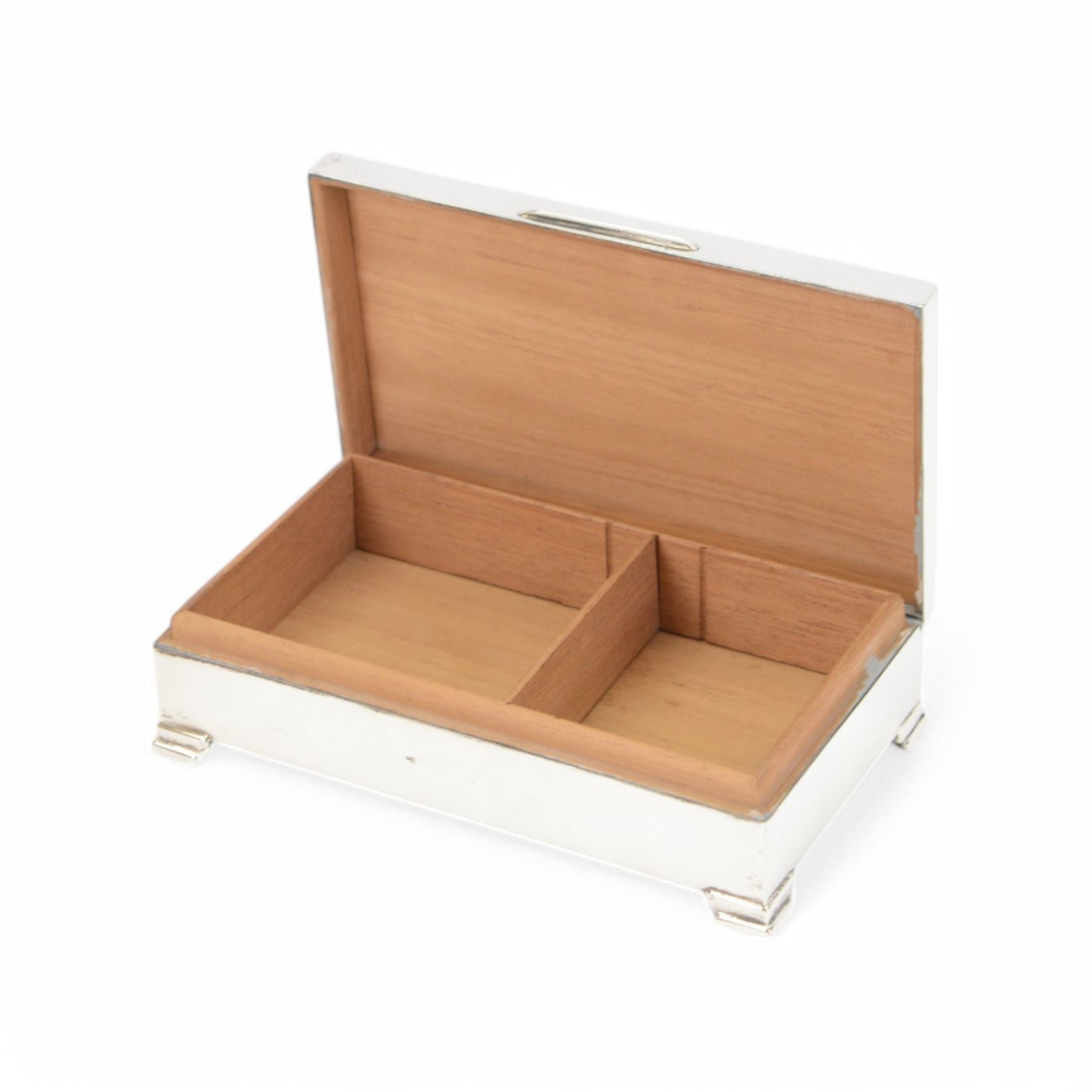 Mid 20th century silver mounted cigarette box, of rectangular form with engine turned decoration to the hinged cover, with vacant rectangular cartouche, opening to reveal a compartmentalised softwood interior, upon four bracket feet, hallmarked Henry Clifford Davis, Birmingham 1964, H4cm, W15cm