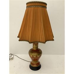 A large table lamp of baluster form, with scrolling gilt decoration upon a red ground, on circular ebonised base, together with a pleated fabric shade, lamp base H53cm. 