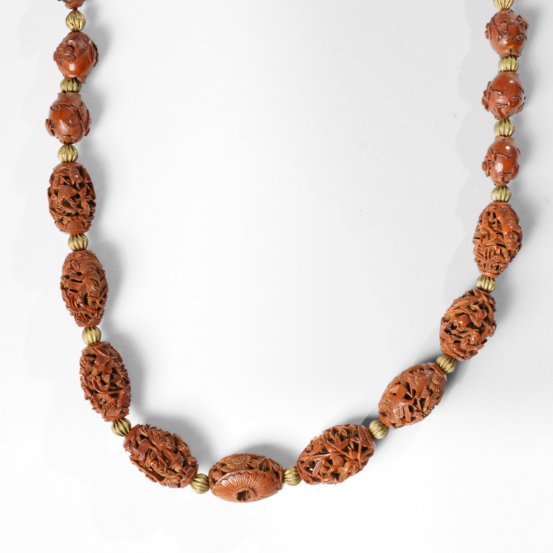 Chinese Hediao necklace, comprising twenty-one pierced and carved seeds strung with smaller beads, the carvings depicting birds among foliage, crabs and fish, figures and warriors, and other traditional scenes, length 82cm 
