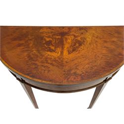 Early 19th century mahogany card table, demi-lune fold-over top with highly figured matched veneers, baize lined interior, the frieze with rosewood bands and figured oval panels, on square tapering supports with spade feet