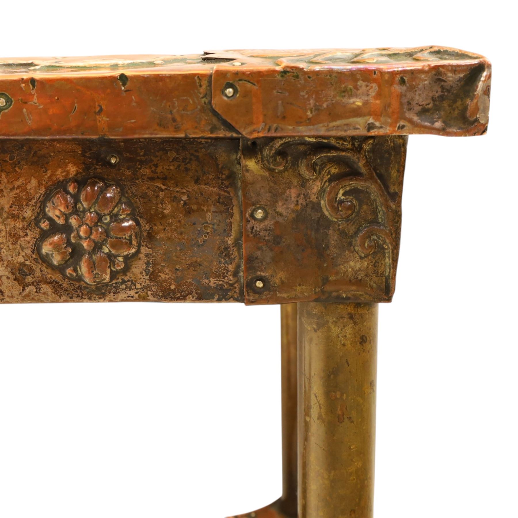 Arts and Crafts copper mounted coffee table, rectangular top with embossed foliate border and stylised corner motifs, studwork detail, on cylindrical supports united by pierced shaped stretcher with applied flowerhead bosses