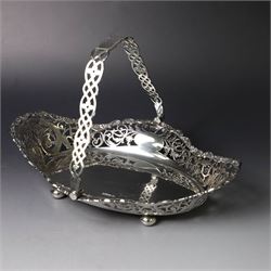 Early 20th century swing handled basket, of oval form with pierced sides and floral C scroll rim, upon four bun feet, hallmarked William Hutton & Sons Ltd, Sheffield 1915, widest point W29cm
