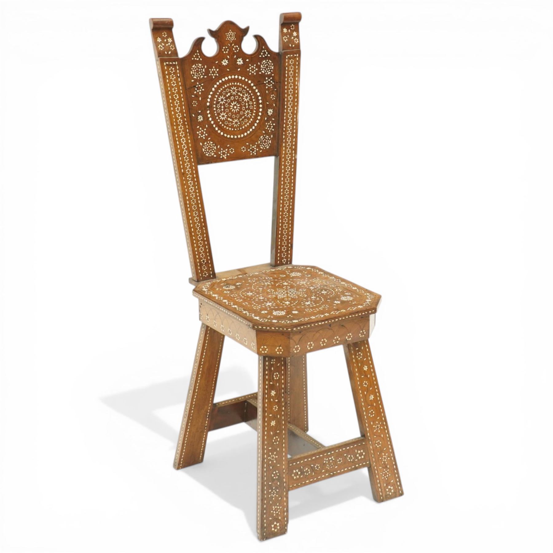 19th century Syrian olive wood and ivory inlaid chair, the shaped back and cresting above a panel centred by a circular starburst roundel within geometric and foliate marquetry and stringing, the tapering uprights and frame extensively inlaid with repeating ivory motifs, the octagonal seat similarly decorated, raised on splayed legs united by H-stretcher with further inlaid ornament