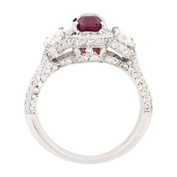 18ct white gold ruby and diamond trilogy ring, single emerald cut ruby of approx 1.85 carat, with a single emerald cut diamond set either side, all surrounded by round brilliant cut diamonds, the shoulders set with three rows of round brilliant cut diamonds, principal two emerald cut diamonds approx 1.10 carat