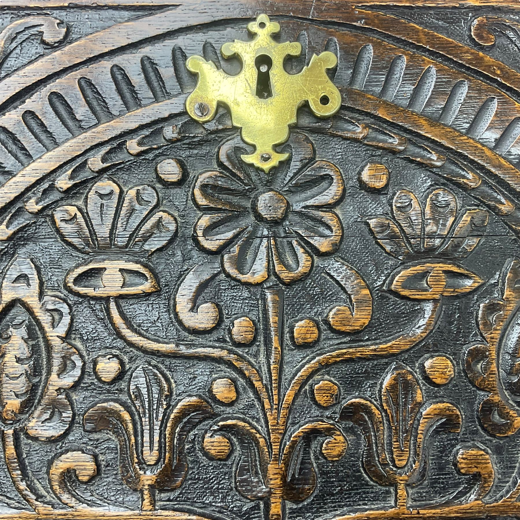 18th century heavily carved oak bureau, the fall front relief carved with three arches enclosing plants and flower head decoration, the interior fitted with pigeonholes, drawers and cupboard, four graduating cock-beaded drawers below, carved with lunettes and trailing foliage decoration, on bracket feet